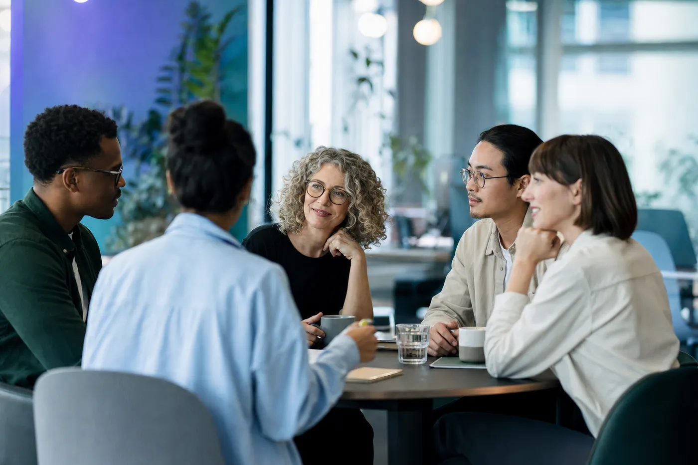 A personality-diverse team of colleagues in genuine conversation around a small round table
